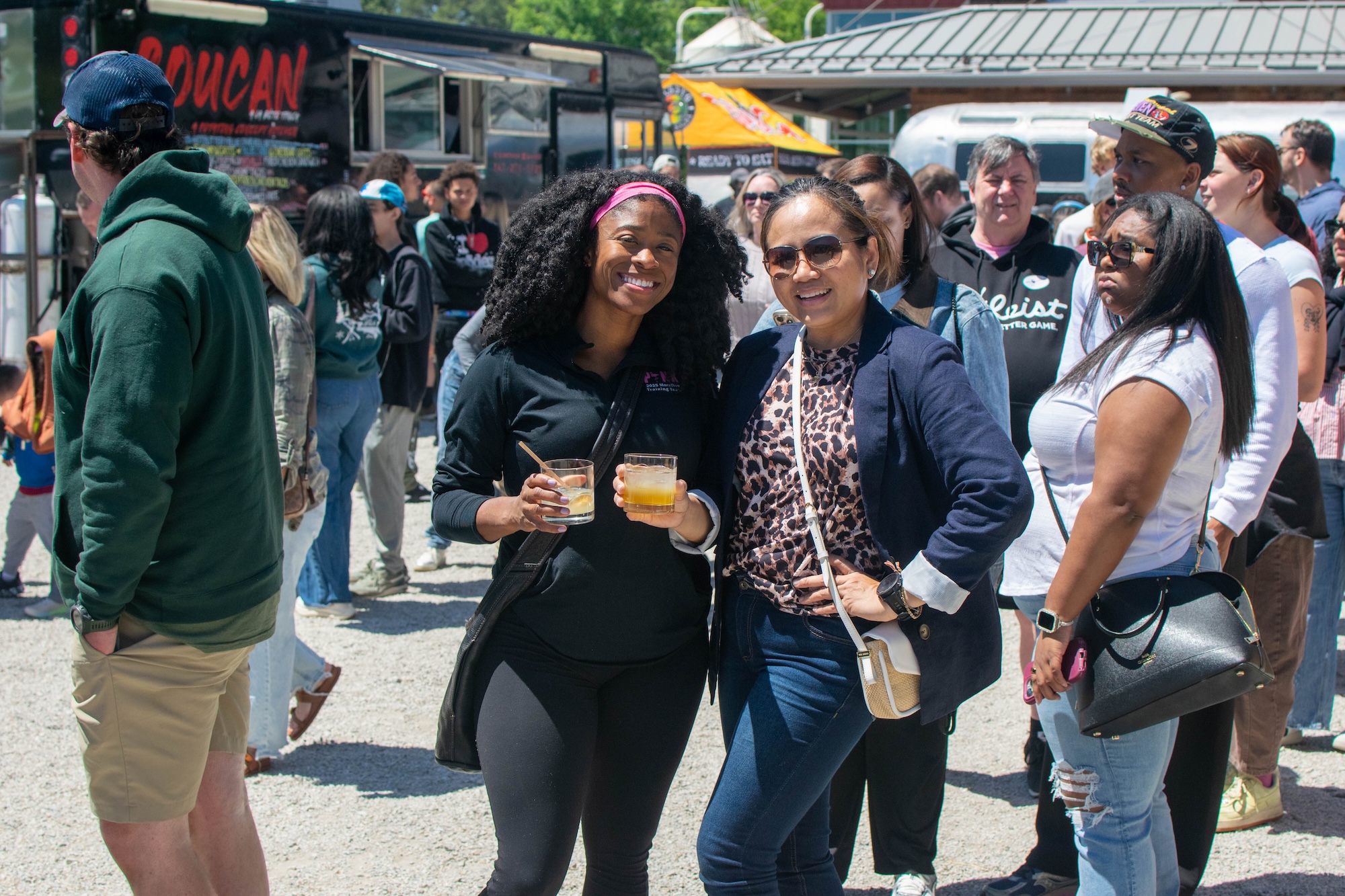 RVA Taco Festival 2026 - Two attendees smiling and holding drinks in front of food trucks